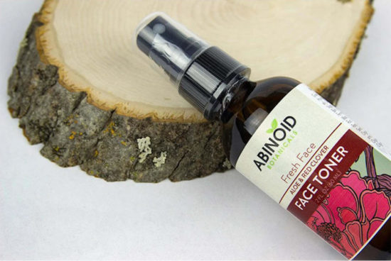 A bottle of Aloe and Clover Face Toner by Abinoid Botanicals on a block of wood
